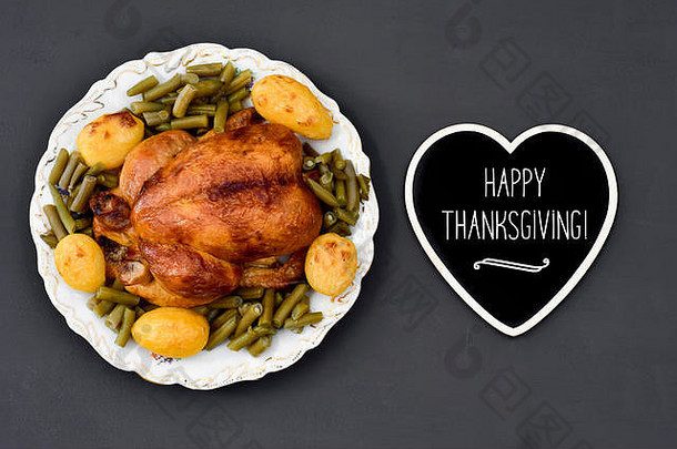 一只烤火鸡放在圆形陶瓷托盘上的高角度镜头，一个心形招牌上写着“感恩节快乐”