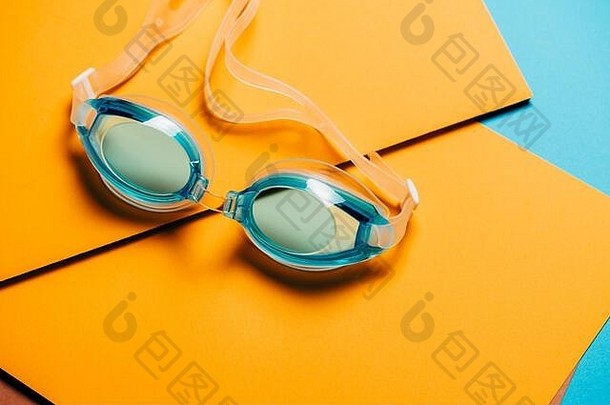 蓝色游泳眼镜，黄色几何背景上有橡胶带。产品概念