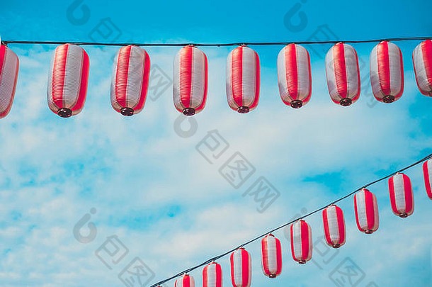 纸红白相间的日本灯笼挂在蓝天的背景上。夏季背景