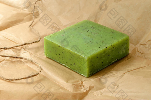 棕色包装纸上的绿色手工草药肥皂条。含有草药和精油的天然化妆品和卫生产品。前视图。