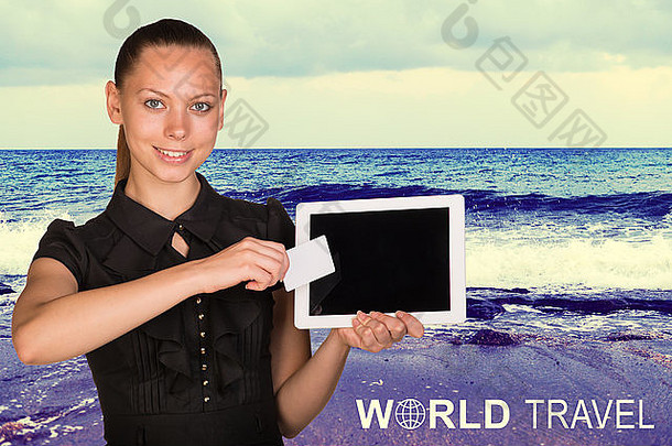 美丽的女商人手持平板电脑和名片在屏幕前。海景作为背景