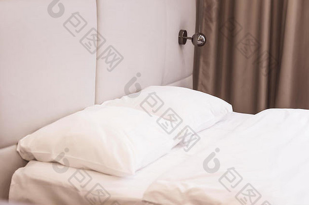 卧室里的床，白色亚麻布，枕头，毯子，壁灯