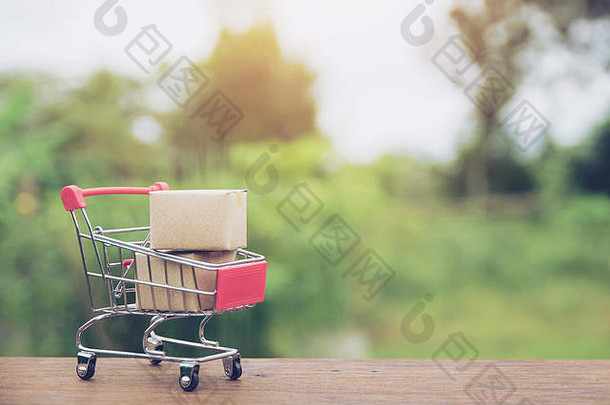 购物理念：在棕色木桌上的购物车中放置纸箱或纸盒。网上购物消费者可以在家购物，并提供送货服务。机智