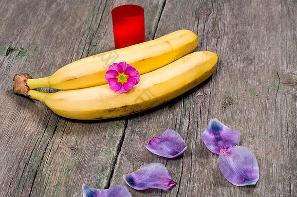 两个用丁香花瓣和红蜡烛装饰的香蕉