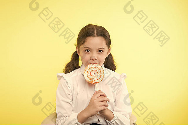 营养不良是一个普遍的问题。女生校服喜欢糖果棒棒糖糖果黄色背景。女孩可爱的孩子马尾辫发型吃甜棒棒糖。适量的糖果可以。