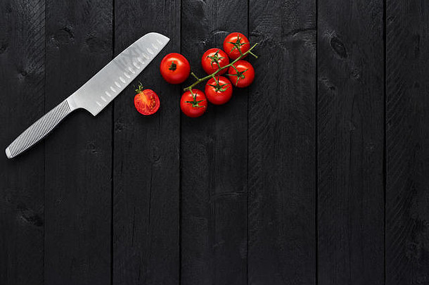 <strong>不锈钢</strong>菜刀和西<strong>红</strong>柿放在黑木桌上，留有复印空间，可供菜单或食谱使用。俯视图，平面布置。食物背景概念。