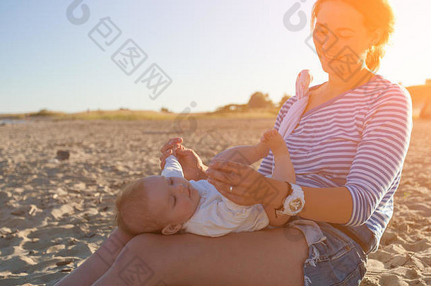 一个快乐的黑发女人，手里抱着一个，在海滩上和她玩耍。海上避暑概念与生活方式