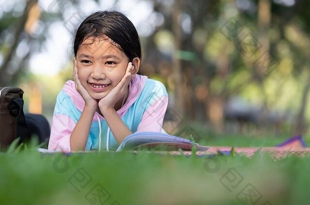亚洲女孩躺把手下巴书微笑草坪上花园孩子阅读书去把握