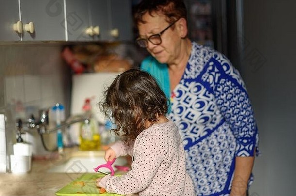 <strong>呆</strong>在家里。现实生活。早餐烹饪过程。<strong>小可爱</strong>的蹒跚学步的小女孩和祖母在厨房里。与孩子一起烹饪，健康食品，家庭之爱。