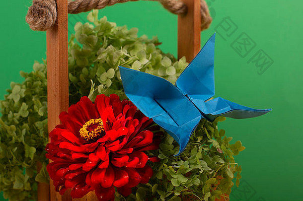 手工艺术折纸蝴蝶在绿色灌木上，在彩色背景上的篮子里，美丽的花束工作室近景拍摄
