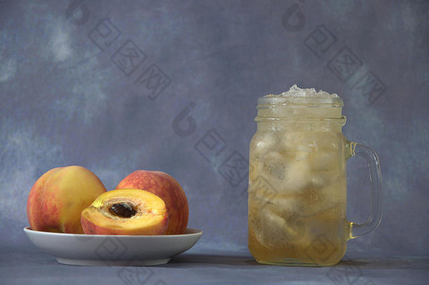 在盘子里放上成熟的<strong>桃</strong>子和一杯加冰的<strong>桃</strong>子汁。特写。