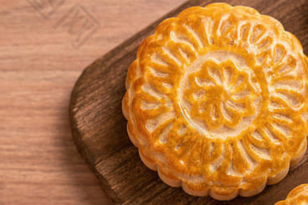 圆形新鲜烘焙月饼糕点-中秋节中国月饼，木质背景和托盘，俯视图，平面布置。