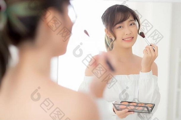 美肖像年轻的亚洲女人微笑脸镜子应用化妆刷脸颊卧室美丽的女孩持有脸红的人