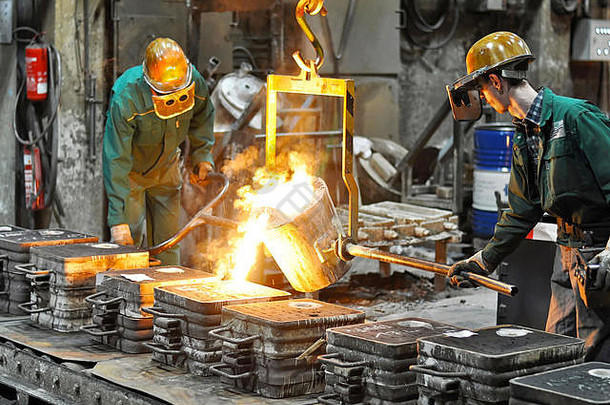 在熔化炉的铸造厂工作的一群工人-在一家工业公司生产铸钢件