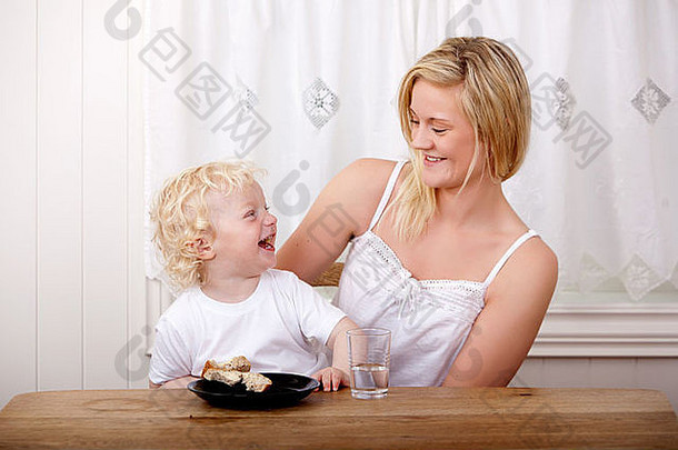母亲和儿子在餐桌旁吃午饭时笑了