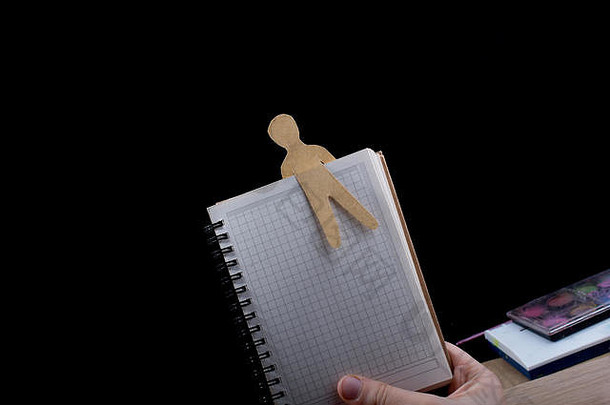 手拿笔记本从纸上剪下的人形