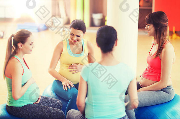 快乐的孕妇坐在健身房的球上