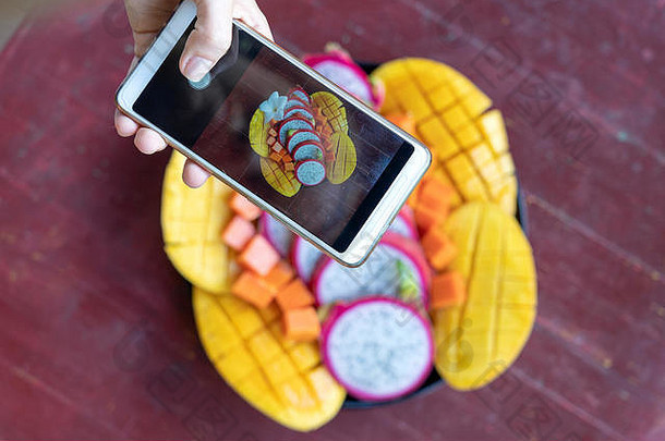 女人手电话摄影热带水果智能手机照片早餐社会媒体写博客甜蜜的芒果木瓜Pitahaya生