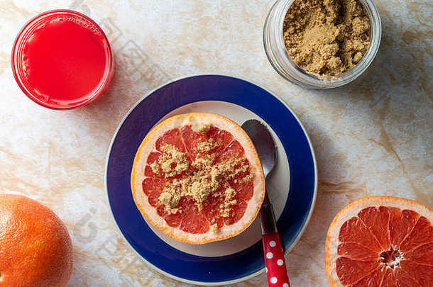 葡萄柚和鲜榨果汁，红糖，健康早餐，放在一个浅色大理石桌面上
