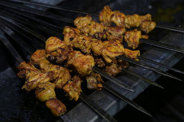 夏季烧烤时，用串肉杆烤辣鸡肉，可近距离观看，食物摄影。