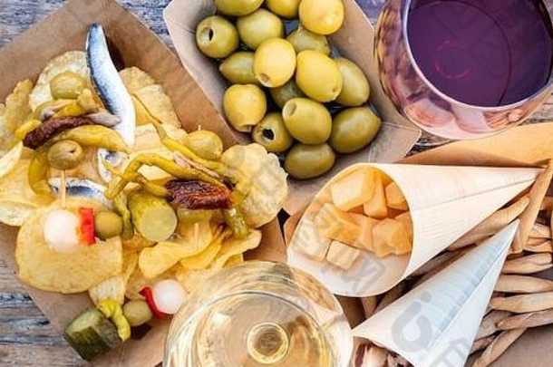 塔帕斯和平丘斯，头顶全景。木桌上放着奶酪、果酱和橄榄、吉尔达斯和薯片，还有一杯红酒和白酒