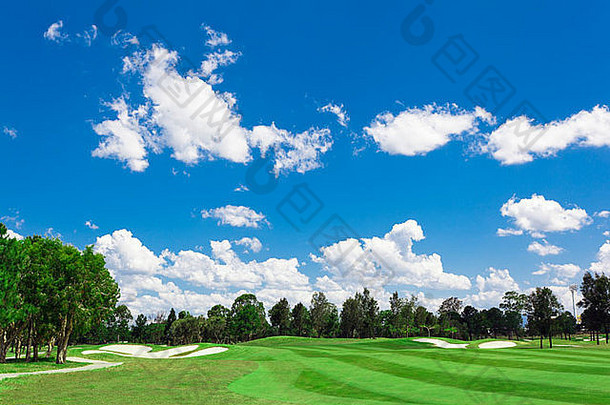 阳光明媚的高尔夫球绿色分散云蓝色的天空森林
