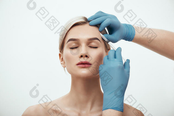 化妆品注射肖像年轻的漂亮的女人保持眼睛关闭<strong>医生</strong>手蓝色的医疗手套使注射肉毒杆菌脸美面部手术