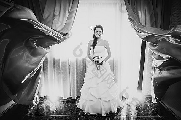黑白摄影美丽的年轻幸福的<strong>新娘</strong>站在窗边