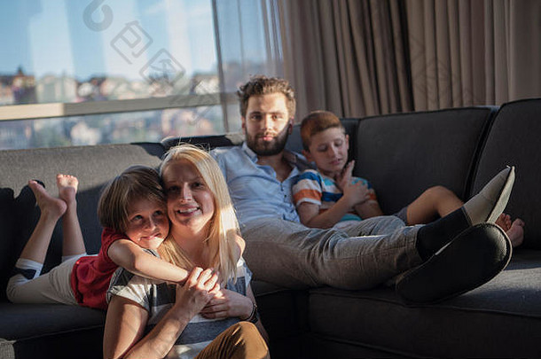 这对幸福的夫妇和孩子们在家里的沙发上玩平板电脑