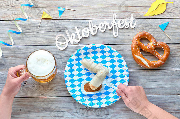 啤酒节，传统节日食品：白香肠，椒盐卷饼和啤酒。平铺在质朴的木桌上，有蓝白相间的格子装饰