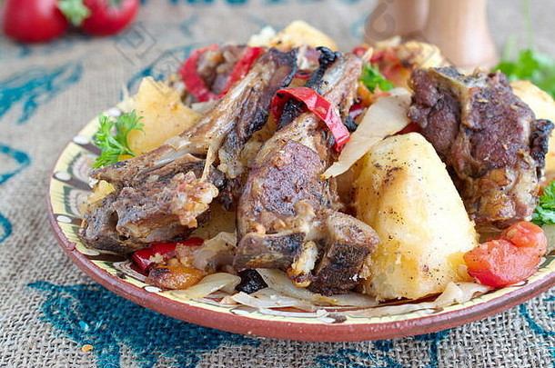 传统炖菜，配羊排和蔬菜：洋葱、卷心菜、土豆、西红柿、辣椒，放在一个碗里，背景是布。健康饮食观念。