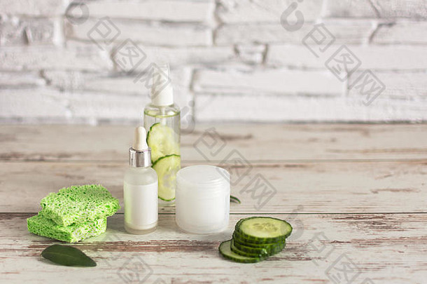 瓶装黄瓜天然化妆品，绿色黄瓜片和棉垫，木质背景。复制空间。