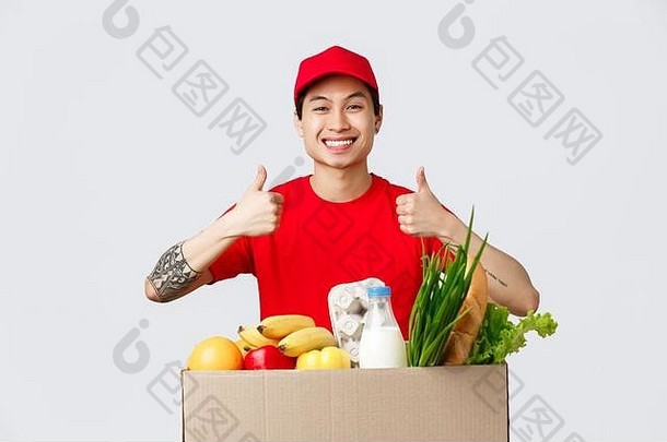网上购物、食品配送和网店概念。身着t恤，头戴红帽，微笑英俊的亚洲信使，竖起大拇指表示赞同，保证