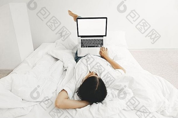 快乐时尚的女孩说谎床上移动PC空白屏幕白色现代房间年轻的女<strong>人</strong>空显示购物在线工作