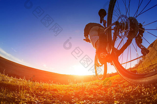 低角视图骑自行车的人站山自行车小道日落