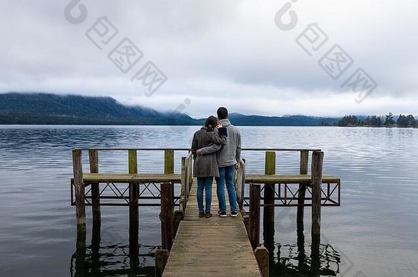 年轻的亚洲夫妇在新西兰的泰安瑙湖大桥上靠在肩膀拥抱