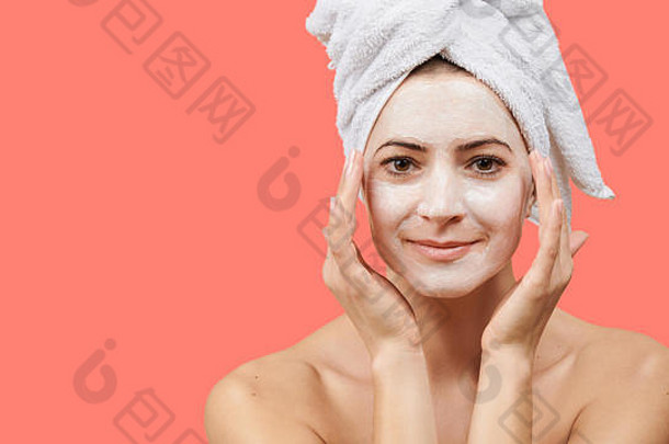 年轻的女人白色浴毛巾头发mouisturizing脸面具健康水疗中心概念珊瑚背景