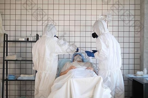 穿着危险品无菌服的医生在医院里测量病人的体温。
