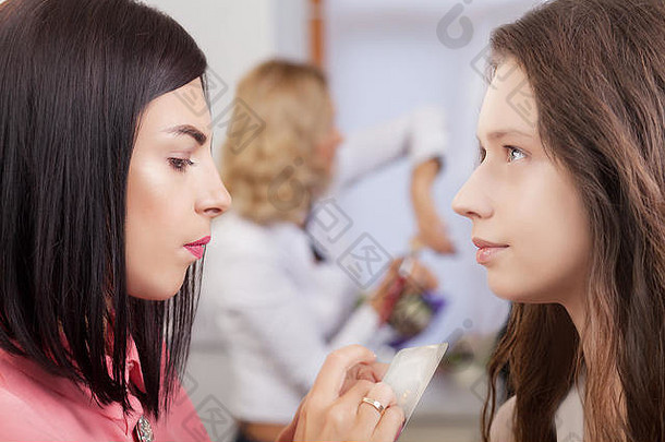 专业化妆师与美丽的年轻女子合作