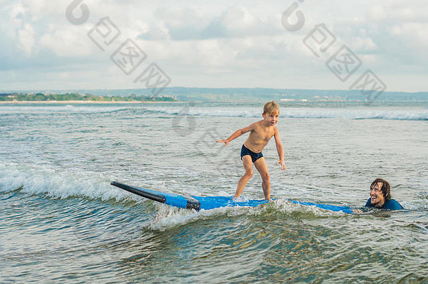 父亲或教练在假期或假日教他4岁的儿子如何在海里冲浪。儿童旅游和体育概念。儿童冲浪课