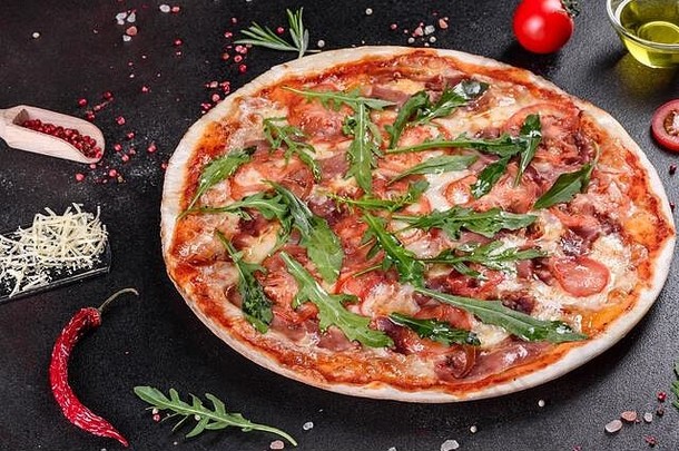 新鲜的比萨饼，用芝麻菜、意大利腊肠、樱桃西红柿和马苏里拉在烤箱里烘烤。意大利菜