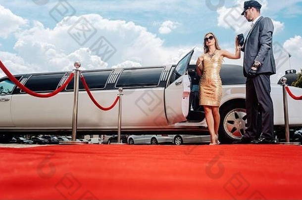 司机帮助贵宾女人明星豪华轿车红色的地毯