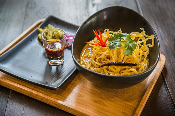 泰国北部传统的风格面条咖喱红色的洋葱泡菜玻璃石油辣椒木板表格
