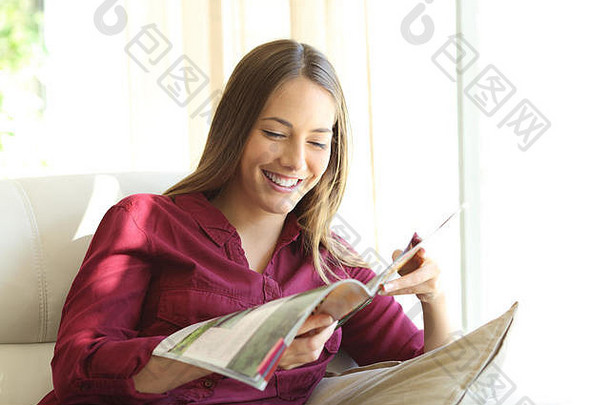 坐在客厅沙发上看杂志的快乐女人