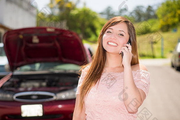 微笑年轻的女人调用报告车损坏的国家路美丽的阳光明媚的一天