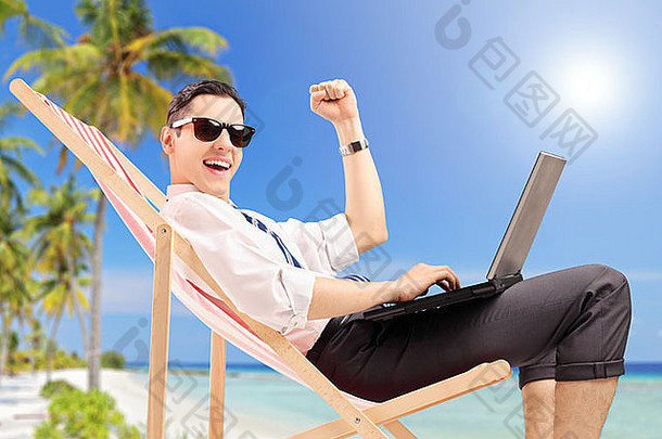 在海滩上拿着笔记本电脑的快乐商人