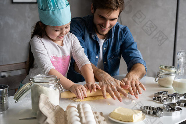 爸爸和小女儿在烤糕点。一家人在厨房里玩得很开心，准备参加聚会。