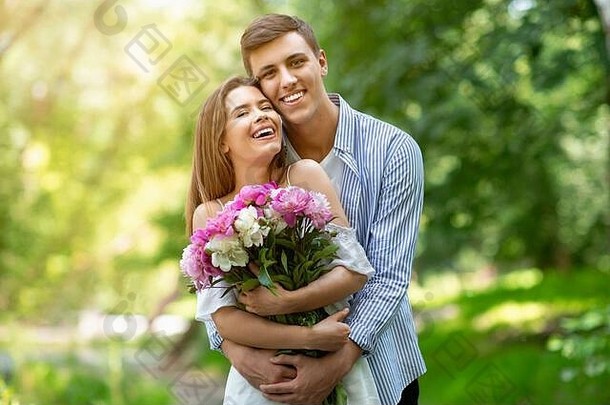 一周年纪念礼物。一对千年夫妇在公园里拥抱鲜花