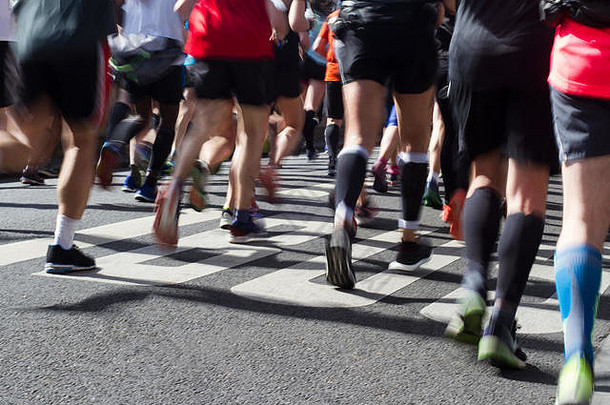 马拉松运动员的脚和腿的特写后视图，运动模糊在城市柏油路上晨光中跑步