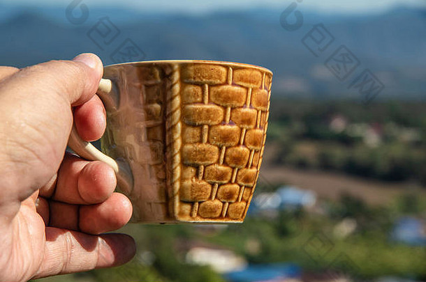 近距离拍摄，手拿<strong>咖啡</strong>杯，从山顶观看。